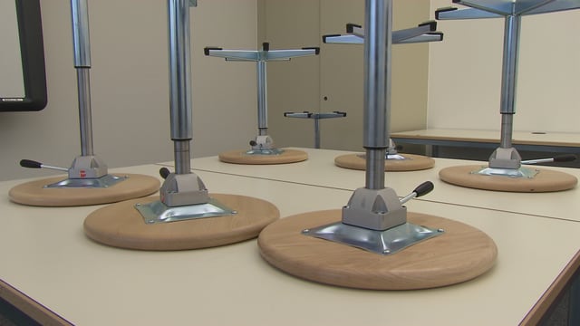 Auf dem Kopf stehende Hocker auf einem Schultisch Auf dem Kopf stehende Hocker auf einem Schultisch