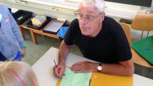 Rene Stöhr korrigiert eine Arbeit, ein Mädchen schaut zu Rene Stöhr korrigiert eine Arbeit, ein Mädchen schaut zu