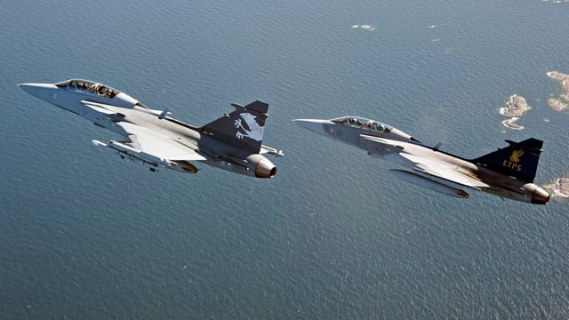 Zwei Kampjets fliegen hintereinander über dem Meer. Zwei Kampjets fliegen hintereinander über dem Meer.