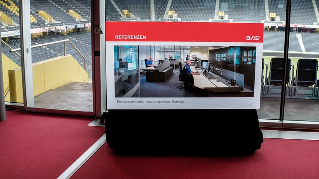 Foto einer Einsatzzentrale auf einem Flachbildschirm, im Hintergrund das Stadion Foto einer Einsatzzentrale auf einem Flachbildschirm, im Hintergrund das Stadion