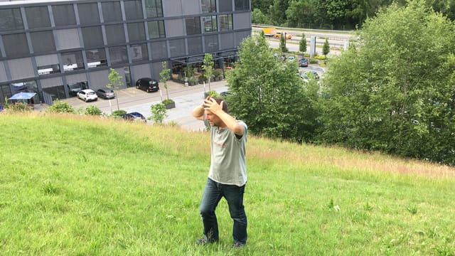 Ein Mann steht händeringend auf einer steilen Wiese. Ein Mann steht händeringend auf einer steilen Wiese.