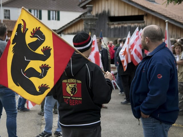 Demonstranten halten Berner und Jura-Flaggen hoch. Demonstranten halten Berner und Jura-Flaggen hoch.