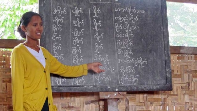 Eine Lehrerin zeigt ihren Schülern etwas an der Wandtafel Eine Lehrerin zeigt ihren Schülern etwas an der Wandtafel