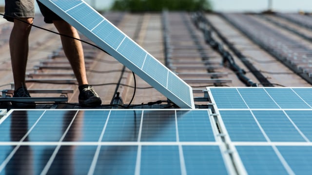 Jemand legt eine Photovoltaïk-Platte auf ein Dach zwecks Installation. Jemand legt eine Photovoltaïk-Platte auf ein Dach zwecks Installation.