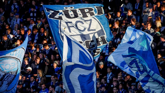 Ein Mann schwenkt eine Fahne des FC Zürich in der Südkurve des Stadions Letzigrund. Ein Mann schwenkt eine Fahne des FC Zürich in der Südkurve des Stadions Letzigrund.