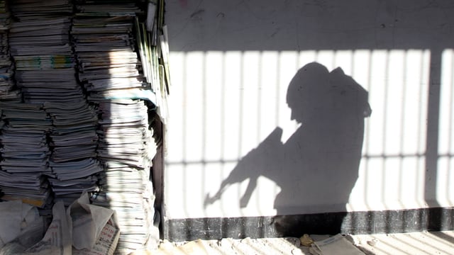 Der Schatten eines Rebellen an der Wand, der mit seinem Gewehr hantiert. Der Schatten eines Rebellen an der Wand, der mit seinem Gewehr hantiert.