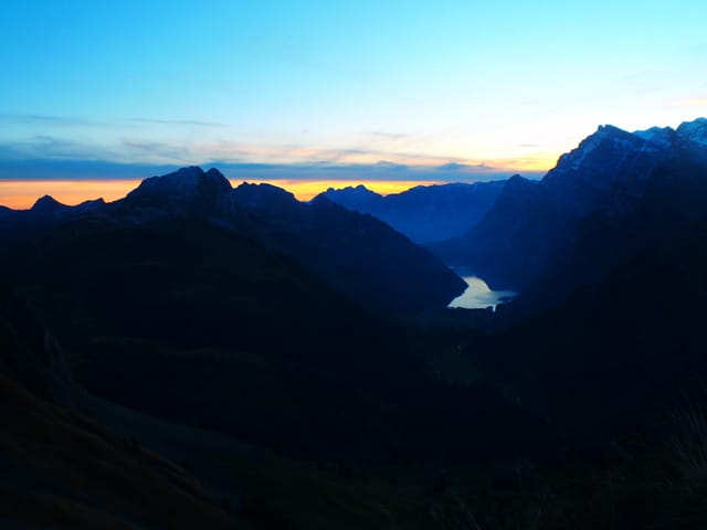 Dunkle Berge im Vordergrund,Morgenrot am Horizont, blauer klarer Himmel