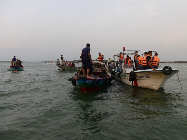 Mehrere Boote, einige der Personen tragen orange Schwimmwesten. Mehrere Boote, einige der Personen tragen orange Schwimmwesten.