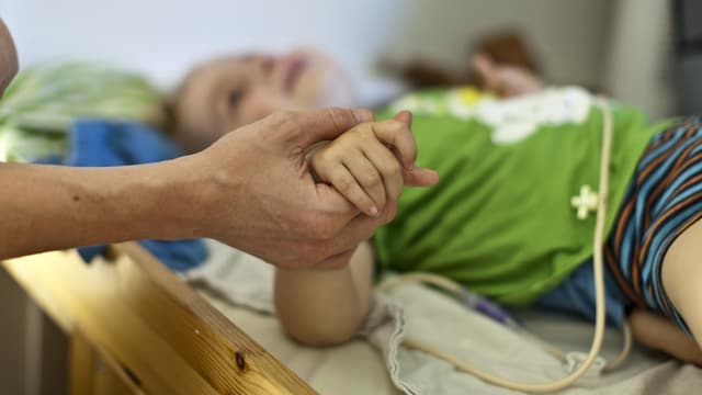 Frau hält Hand von krankem Kind Frau hält Hand von krankem Kind