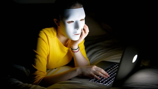 Eine Frau mit weisser Maske sitzt vor dem Laptop. Eine Frau mit weisser Maske sitzt vor dem Laptop.