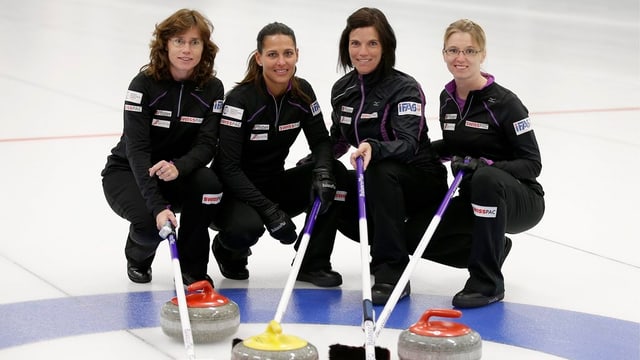 Das Curling-Team posiert mit Steinen und Besen auf dem Eis. Das Curling-Team posiert mit Steinen und Besen auf dem Eis.