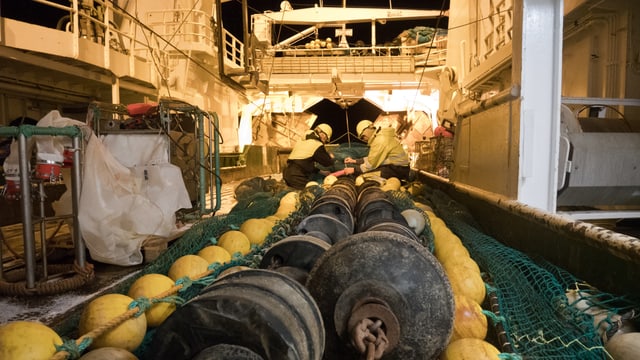 Auf dem Deck eines Schiffs liegt ein grosses Netz, Schwimmer und Ketten. Auf dem Deck eines Schiffs liegt ein grosses Netz, Schwimmer und Ketten.