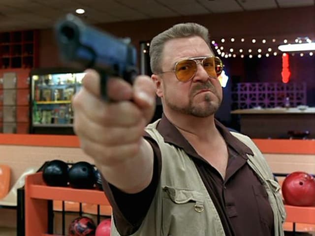 Walter Sobchak in «The Big Lebowsky» mit Brille, Gilet und einer Pistole, mit der er zielt. Walter Sobchak in «The Big Lebowsky» mit Brille, Gilet und einer Pistole, mit der er zielt.