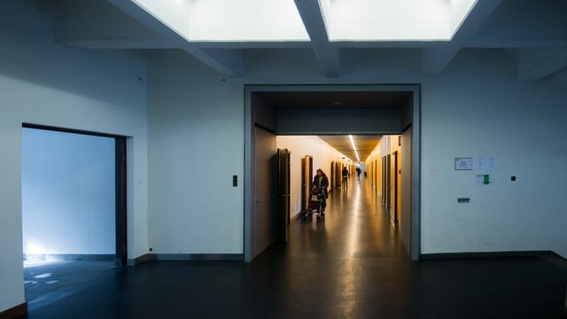 Ein düsterer Gang im Bundesasylzentrum Losone und eine Frau. Ein düsterer Gang im Bundesasylzentrum Losone und eine Frau.