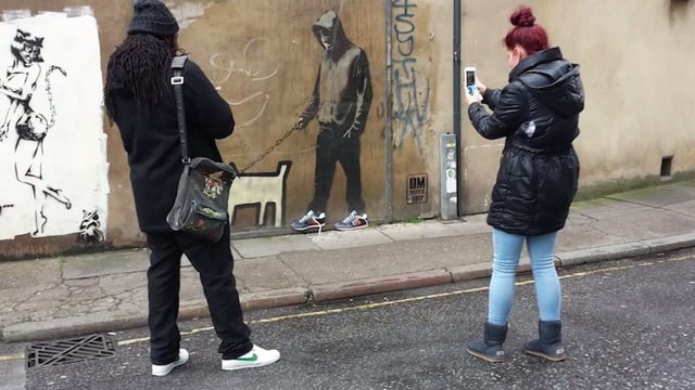 Zwei Menschen stehen vor einem Graffiti mit Turnschuhen. Zwei Menschen stehen vor einem Graffiti mit Turnschuhen.