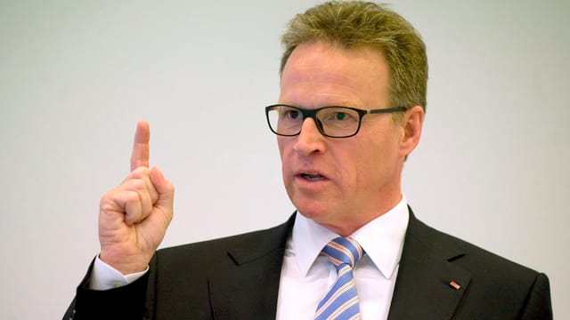Ein Mann mit Brille redet und hat den rechten Arm gehoben Ein Mann mit Brille redet und hat den rechten Arm gehoben