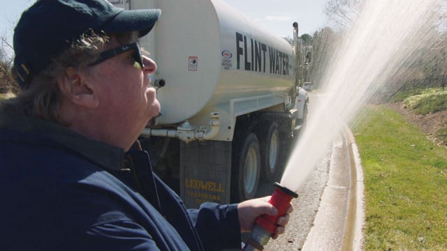 Michael Moore giesst mit Wasser aus Flint einen Garten. Michael Moore giesst mit Wasser aus Flint einen Garten.