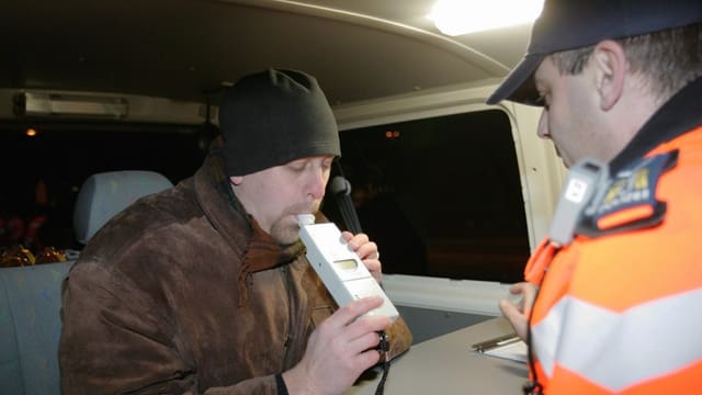 Ein Autolenker bläst in ein Alkohol-Messgerät Ein Autolenker bläst in ein Alkohol-Messgerät