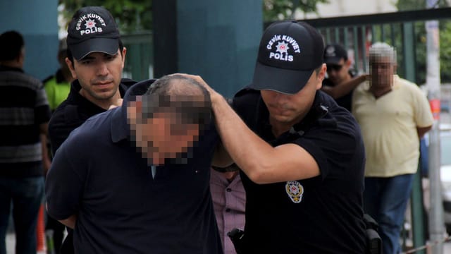 Zwei Polizisten führen einen Soldaten in Zivil mit gesenktem Kopf ab. Zwei Polizisten führen einen Soldaten in Zivil mit gesenktem Kopf ab.