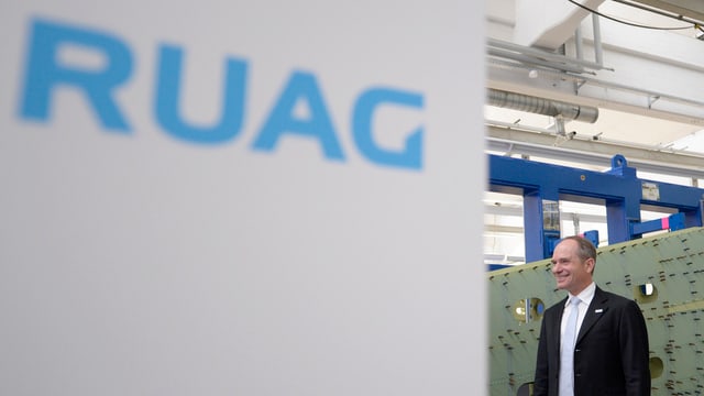 Urs Breitmeier rechts neben einem Schild mit blauem Schriftzug «RUAG» Urs Breitmeier rechts neben einem Schild mit blauem Schriftzug «RUAG»