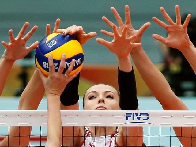Viele Hände greifen nach einem Block-Ball am Netz. Viele Hände greifen nach einem Block-Ball am Netz.