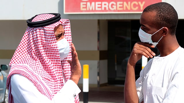 Zwei Männer mit Atemschutzmaske vor einem Krankenhaus in Damman, Saudiarabien. Zwei Männer mit Atemschutzmaske vor einem Krankenhaus in Damman, Saudiarabien.