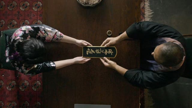 Zwei Menschen von oben gesehen, deren Hände eine Tafel mit japanischen Schriftzeichen halten. Zwei Menschen von oben gesehen, deren Hände eine Tafel mit japanischen Schriftzeichen halten.