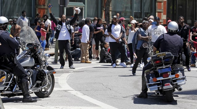 Protestierende werden von zwei Polizisten auf Motorrädern beobachtet. Protestierende werden von zwei Polizisten auf Motorrädern beobachtet.