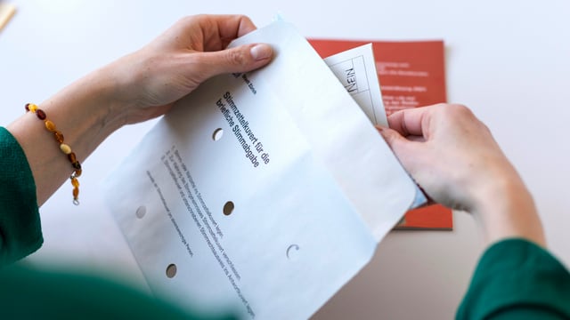 Zwei Hände stcken Stimmzettel in ein Couvert Zwei Hände stcken Stimmzettel in ein Couvert