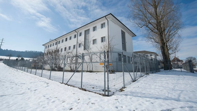 Gebäude der Strafanstalt Hindelbank im Schnee mit Zaun um das Gelände. Gebäude der Strafanstalt Hindelbank im Schnee mit Zaun um das Gelände.