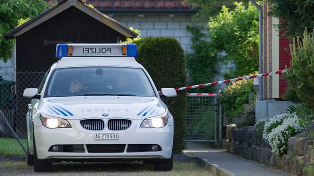 Polizeiauto in Hauseinfahrt, der mit Polizeiband abgesperrt ist Polizeiauto in Hauseinfahrt, der mit Polizeiband abgesperrt ist