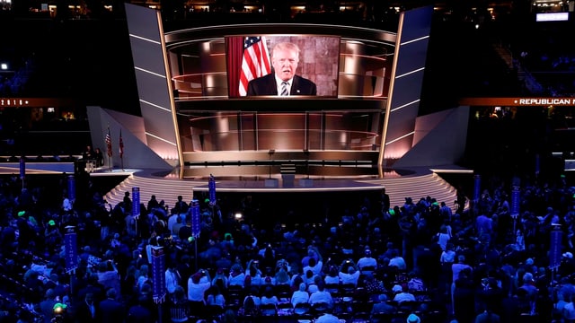 Menschen schauen auf eine Leinwand, auf der Donald Trump zu sehen ist. Menschen schauen auf eine Leinwand, auf der Donald Trump zu sehen ist.