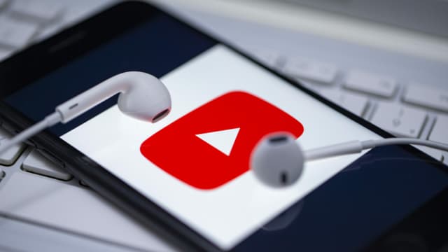 ein Handy mit einem YouTube-Logo und Kopfhörern ein Handy mit einem YouTube-Logo und Kopfhörern