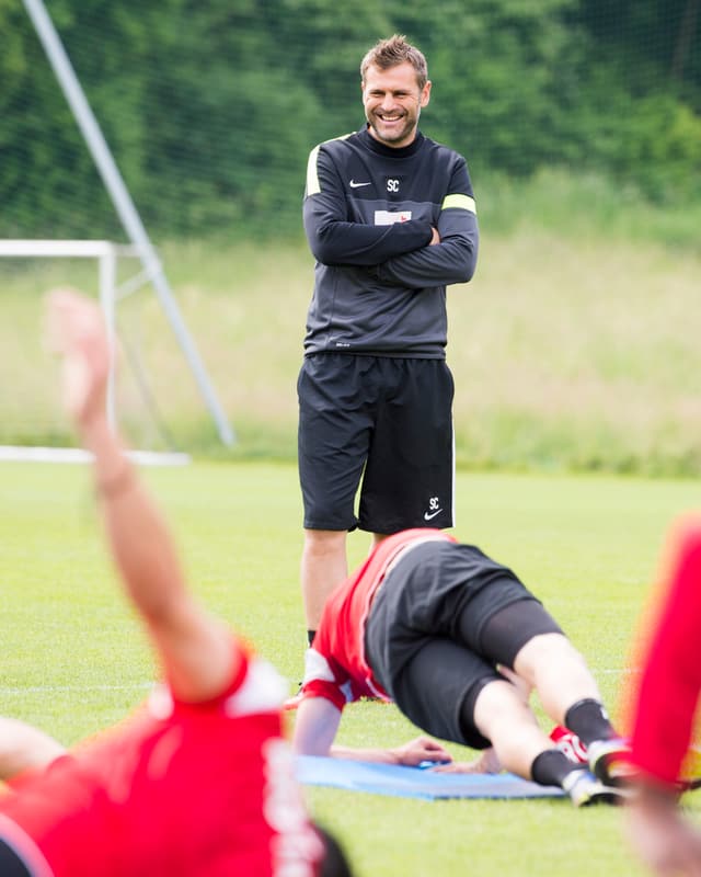 Sven Christ lachend und stehend, im Vordergrund Spieler bei Bodenübungen. Sven Christ lachend und stehend, im Vordergrund Spieler bei Bodenübungen.