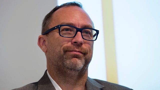 Jimmy Wales mit Anzug und Brille vor einer weissen Wand. Jimmy Wales mit Anzug und Brille vor einer weissen Wand.