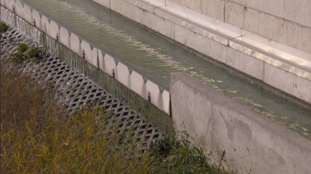 Eine Betonrinne. Von dort fliesst klares Wasser hinunter in einen Bach. Eine Betonrinne. Von dort fliesst klares Wasser hinunter in einen Bach.