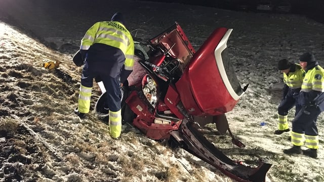 Autowrack an Hang umgeben von Feuerwehrmännern. Autowrack an Hang umgeben von Feuerwehrmännern.