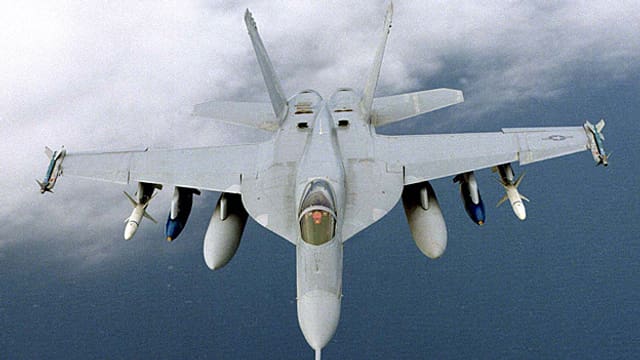 Ein mit Raketen und Zusatztanks bestückter FA18-Kampfflugzeug in der Luft. Ein mit Raketen und Zusatztanks bestückter FA18-Kampfflugzeug in der Luft.