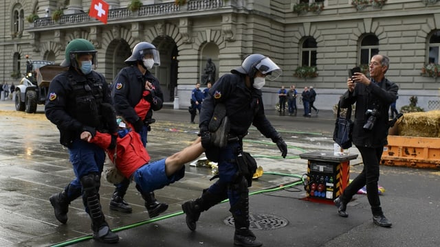 Polizisten tragen eine Person davon. Polizisten tragen eine Person davon.
