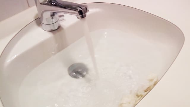 Ein Lavabo. Der Abfluss ist mit Papiertürchern verstopft. Ein Lavabo. Der Abfluss ist mit Papiertürchern verstopft.