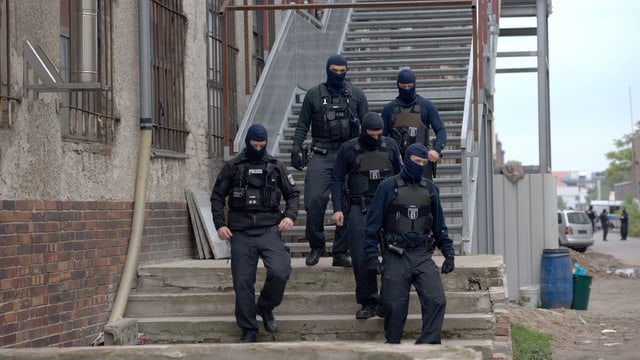 Polizisten mit Masken verlassen ein Gebäude auf einer Treppe. Polizisten mit Masken verlassen ein Gebäude auf einer Treppe.