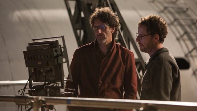 Joel und Ethan Coen, stehend auf einen Bildschirm schauend. Joel und Ethan Coen, stehend auf einen Bildschirm schauend.