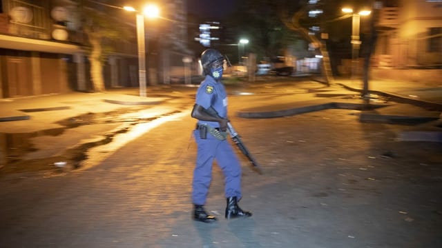 Ein Polizist mit Gewehr steht in einer leeren Strasse in Johannesburg, um die Ausgangssperre während des 2. Lockdowns zu kontrollieren. Ein Polizist mit Gewehr steht in einer leeren Strasse in Johannesburg, um die Ausgangssperre während des 2. Lockdowns zu kontrollieren.
