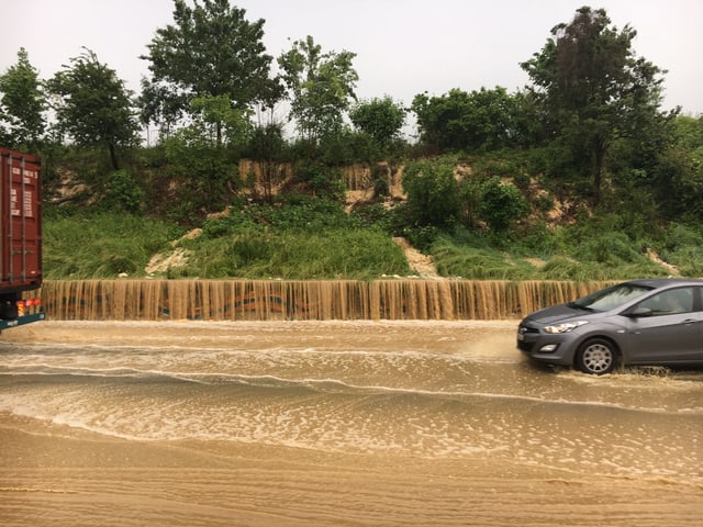 Wasser auf Strasse und Autos, die versuchen, das Wasser zu queren. Wasser auf Strasse und Autos, die versuchen, das Wasser zu queren.