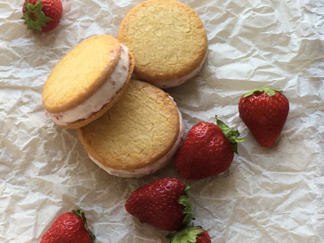 Drei flache Biskuits, gefüllt mit Erdbeerglacé und Erbeeren. Drei flache Biskuits, gefüllt mit Erdbeerglacé und Erbeeren.