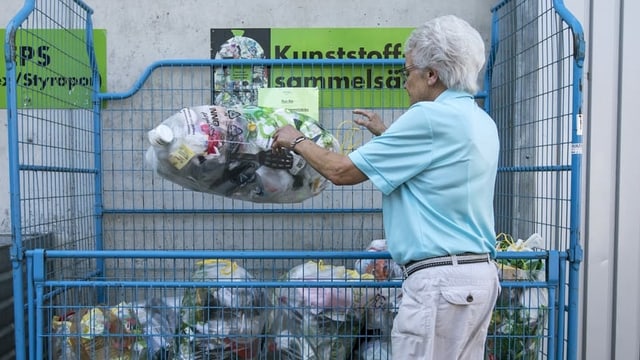 Frau legt Sack mit Plastikabfällen in einen Gitterkasten Frau legt Sack mit Plastikabfällen in einen Gitterkasten