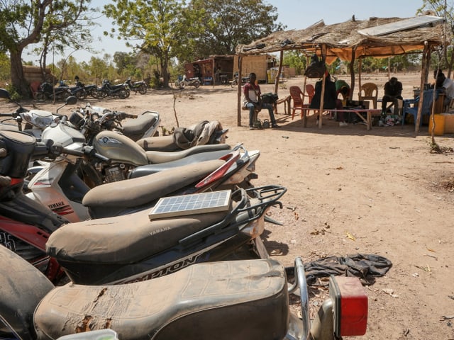 Motorräder, im Hintergrund Menschen in Unterstand Motorräder, im Hintergrund Menschen in Unterstand