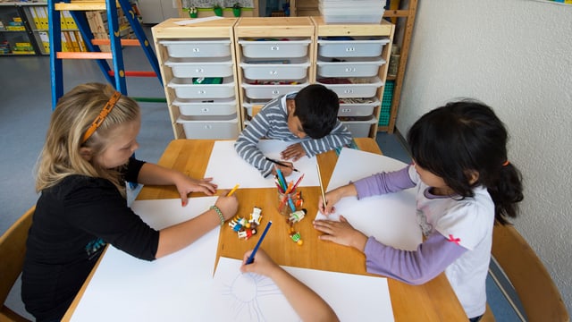 Drei Kinder malen an einem Tisch. Drei Kinder malen an einem Tisch.