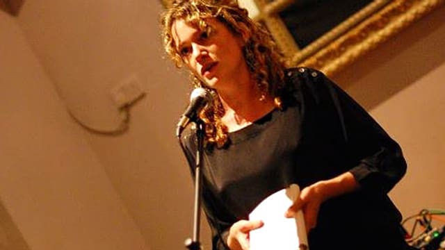 Porträt von Anna Stothard, die vor einem Mikrophon und ein Buch hält. Porträt von Anna Stothard, die vor einem Mikrophon und ein Buch hält.