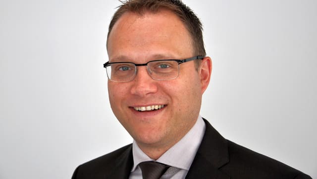 Porträtbild von Damian Meier vor grauem Hintergrund. Porträtbild von Damian Meier vor grauem Hintergrund.